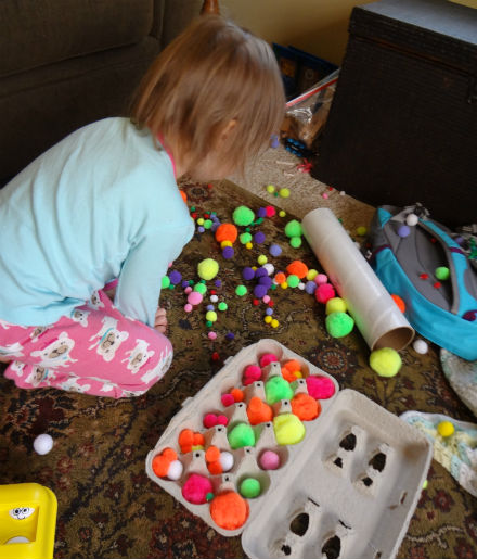 Big sister picking up pom poms