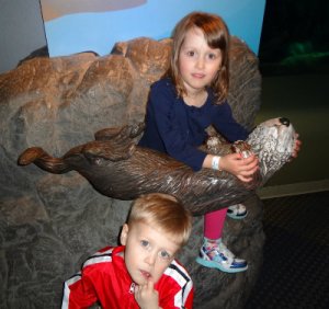 Big sister cradling the otter by their exhibit. Little brother not interested in smiling...